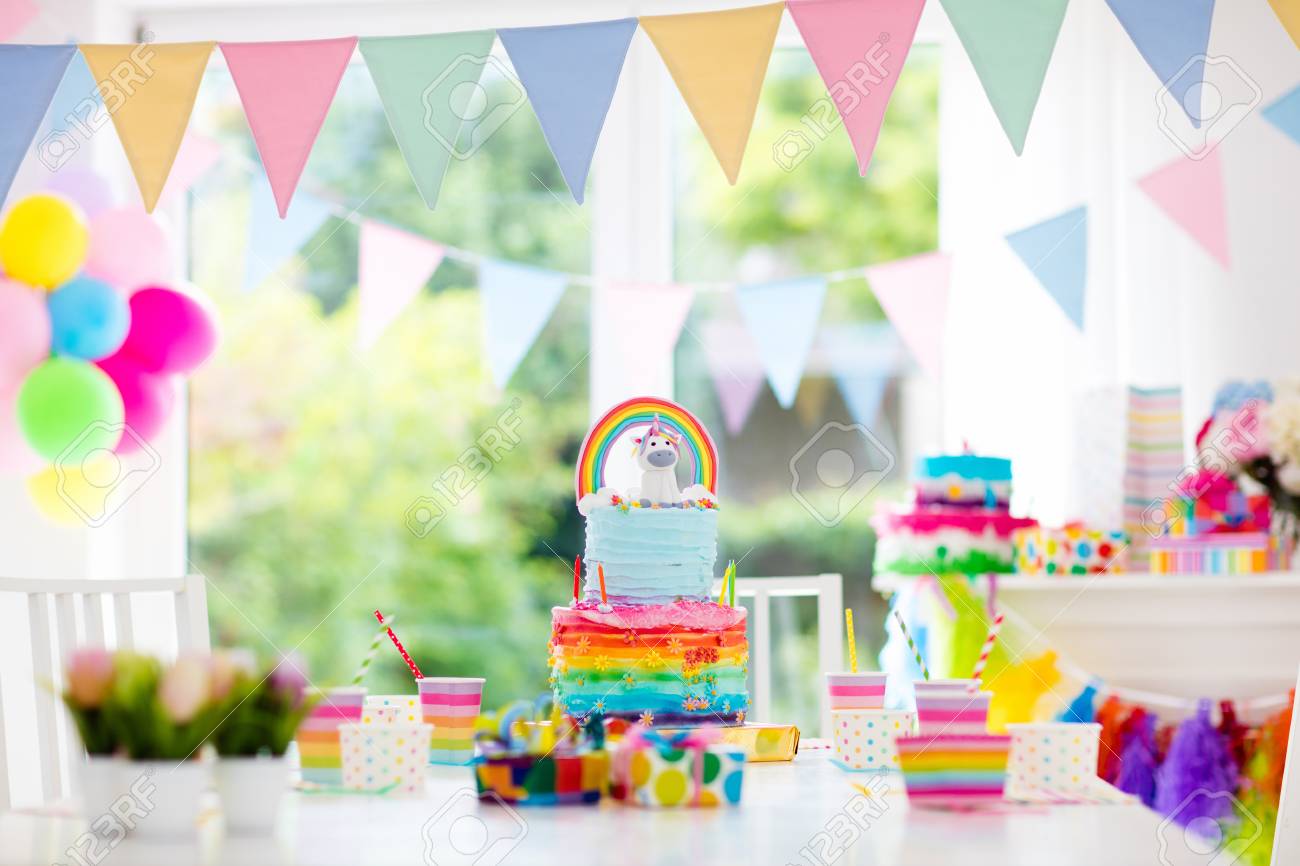 Kids birthday party decoration and cake. Decorated table for child birthday celebration. Rainbow unicorn cake for little girl. Room with festive balloons, colorful banners in baby pastel color. - 78956893 Kids birthday party decoration and cake. Decorated table for child birthday celebration. Rainbow unicorn cake for little girl. Room with festive balloons, colorful banners in baby pastel color. - 78956893