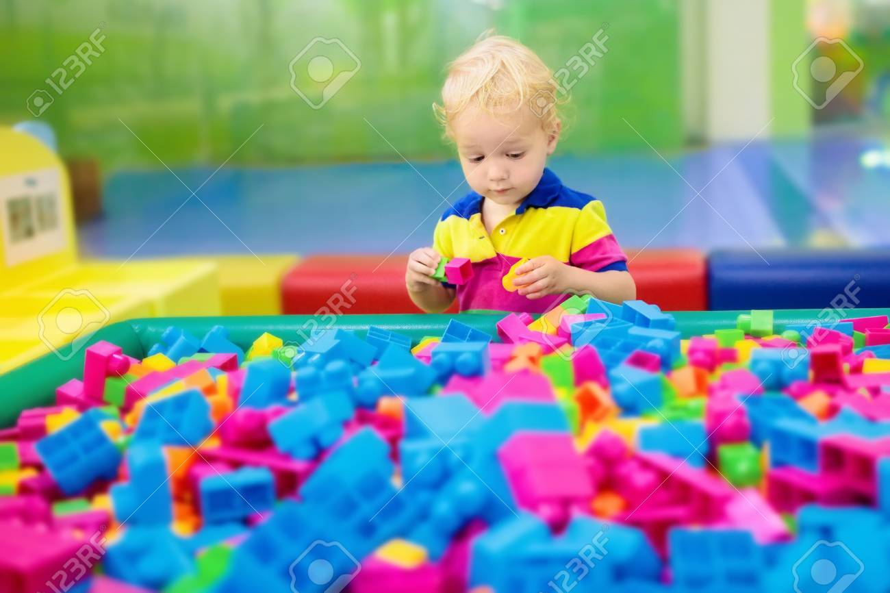 カラフルな建設おもちゃのブロックで遊ぶ子供 若い子供のための教育玩具 幼稚園や幼稚園のプレイルーム デイケアの遊び場で幼児の子供 保育園でブロック付きの少年ビルの家 の写真素材 画像素材 Image
