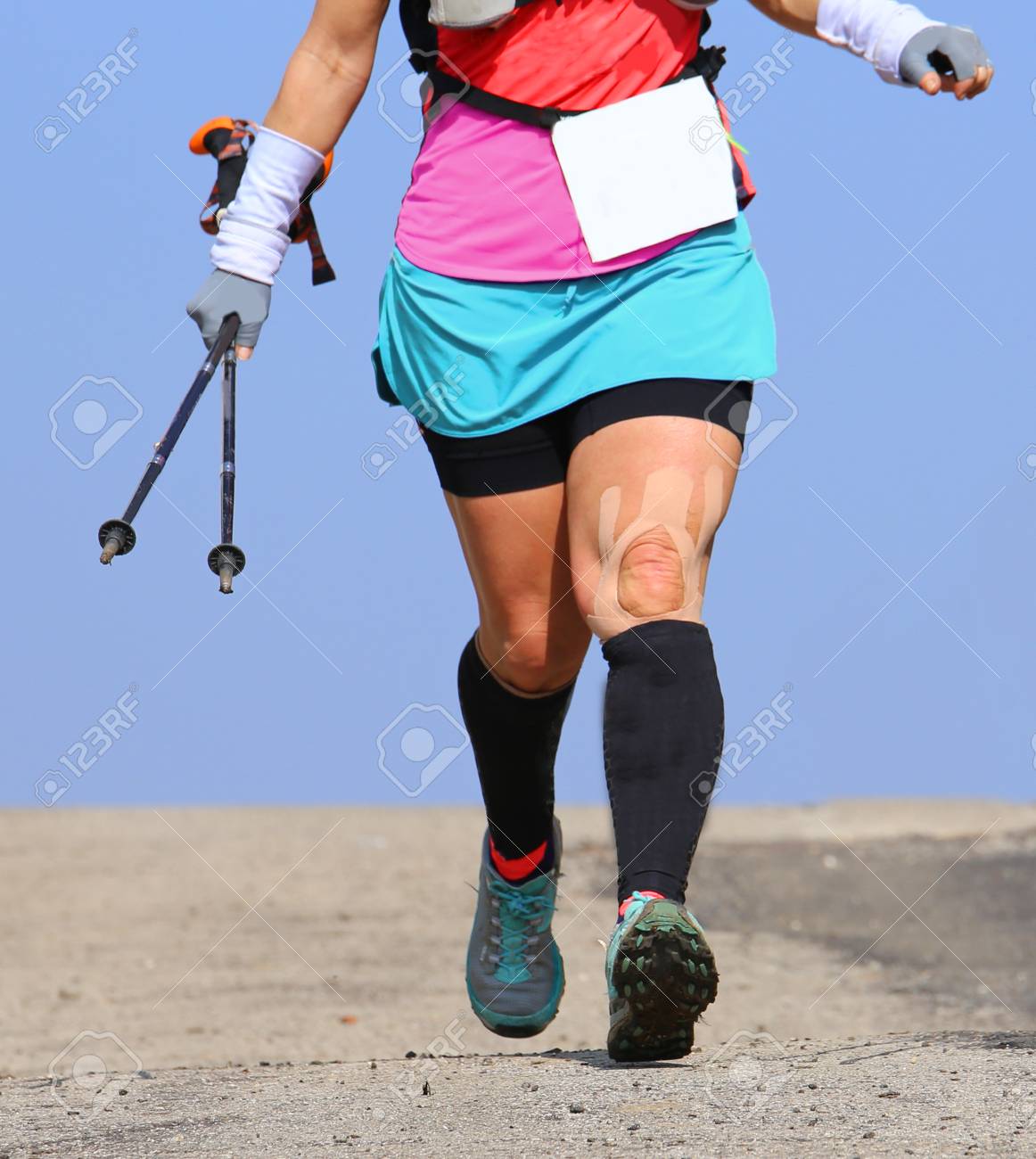 Mujer Corre Con Vendaje En La Rodilla Y Con Los Polos Nórdicos Fotos, Retratos, Imágenes Y Fotografía De Archivo Libres De Image 73885595.