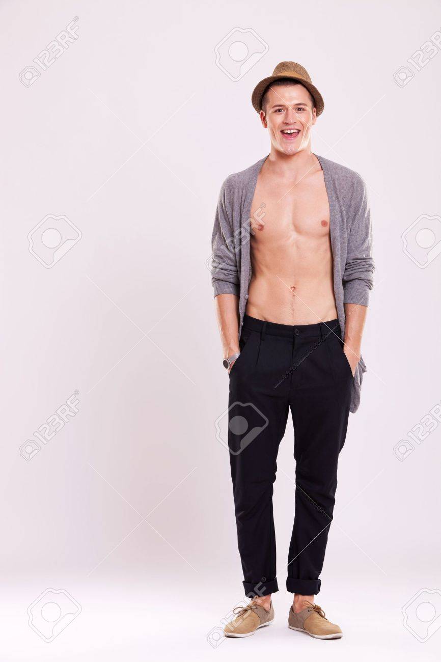 photo Men With Light Abs portrat einer jungen casual mann halt seine hande in die hosentaschen und die enthullung seiner abs wahrend lachelnd in die kamera auf einem hellen