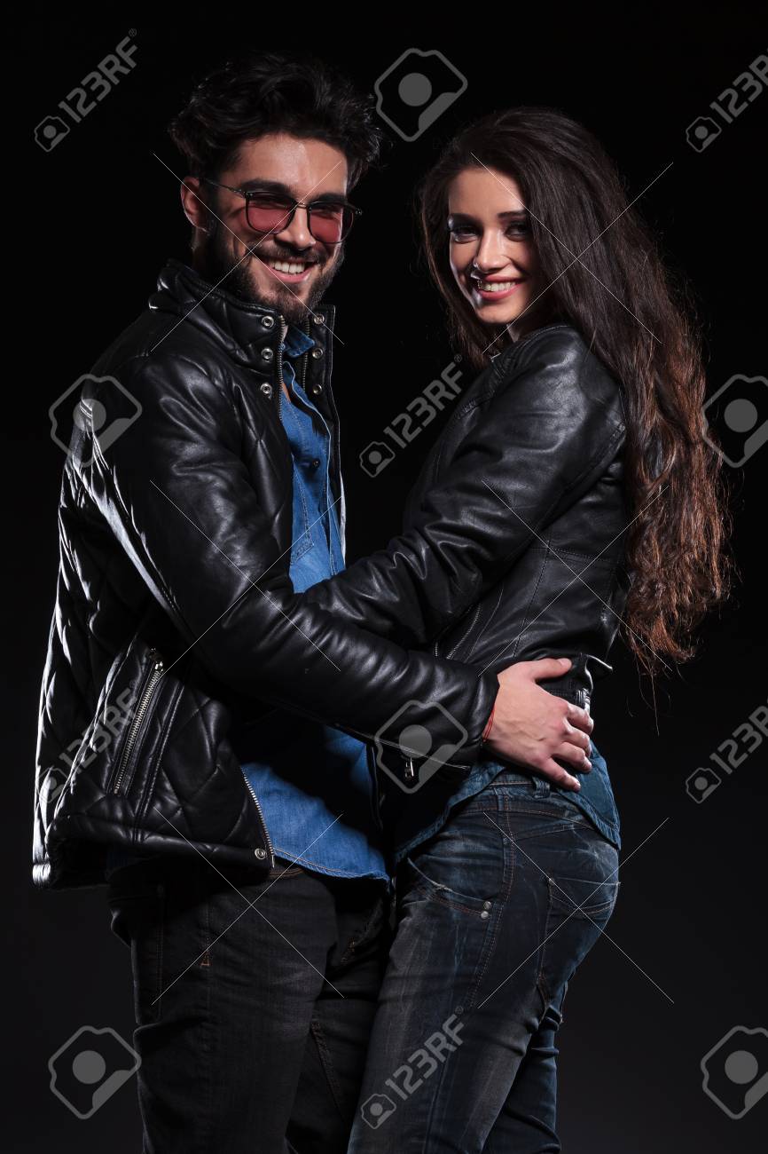 Pareja De Moda Joven En La Chaqueta De Cuero De Pie Abrazado Y Sonríe A La Cámara Fotos, Imágenes Y Fotografía De Archivo Libres De Derecho. Image 23422891.