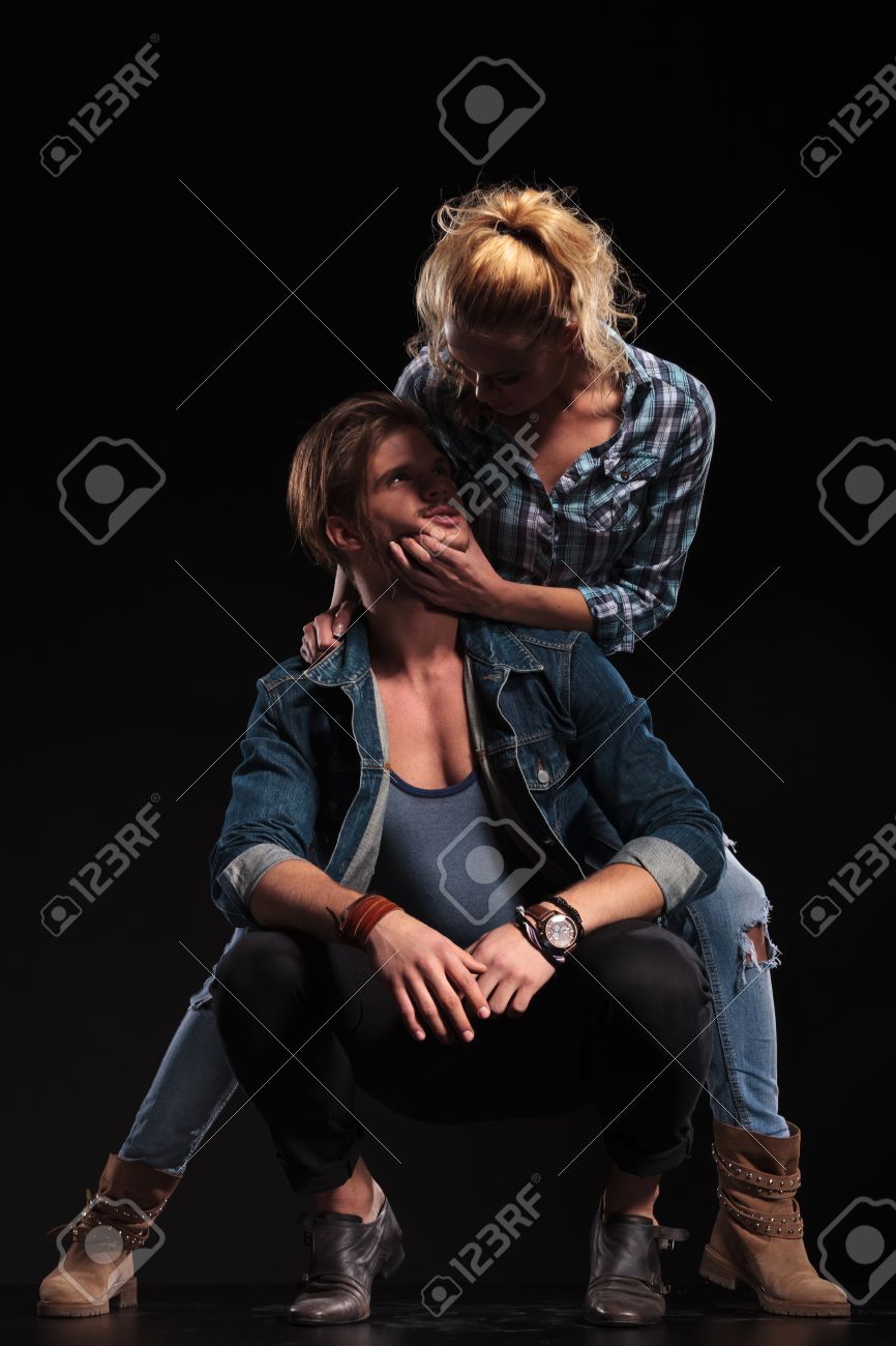 カジュアルなセクシーなカップルは彼にキスをしようとしている男のあごを保持している女性をカメラにポーズ の写真素材 画像素材 Image