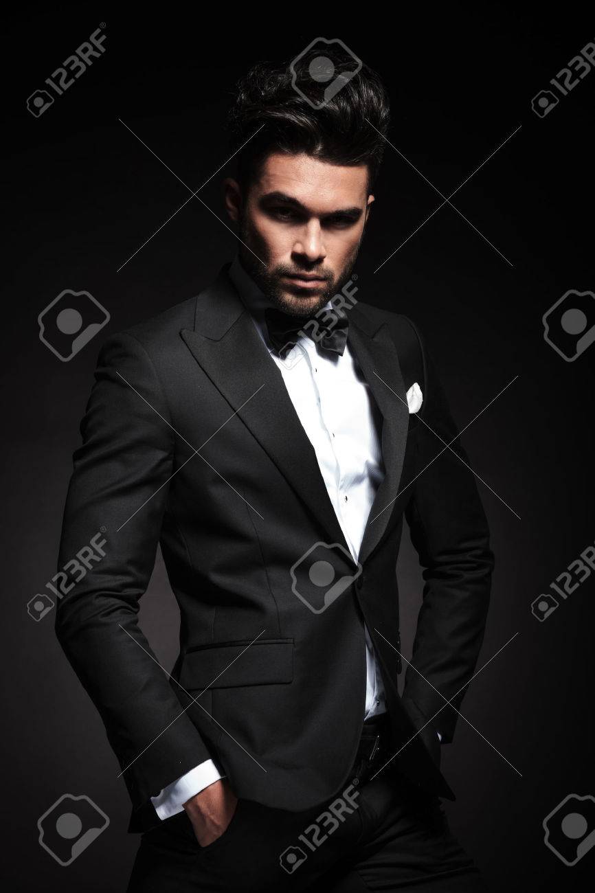 Attractive young business man looking at the camera while holding both hands in his pocket. - 47359655 Attractive young business man looking at the camera while holding both hands in his pocket. - 47359655
