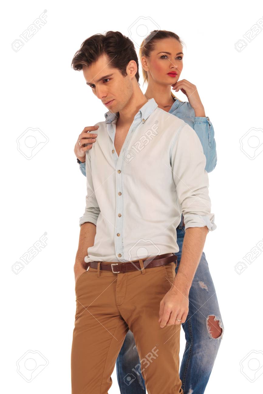 Presentacion Del Hombre Que Mira Lejos De La Camara Con La Mano En El Bolsillo Mientras Que La Mujer Esta En Contacto Con El Por Detras En El Hombro En El Fondo