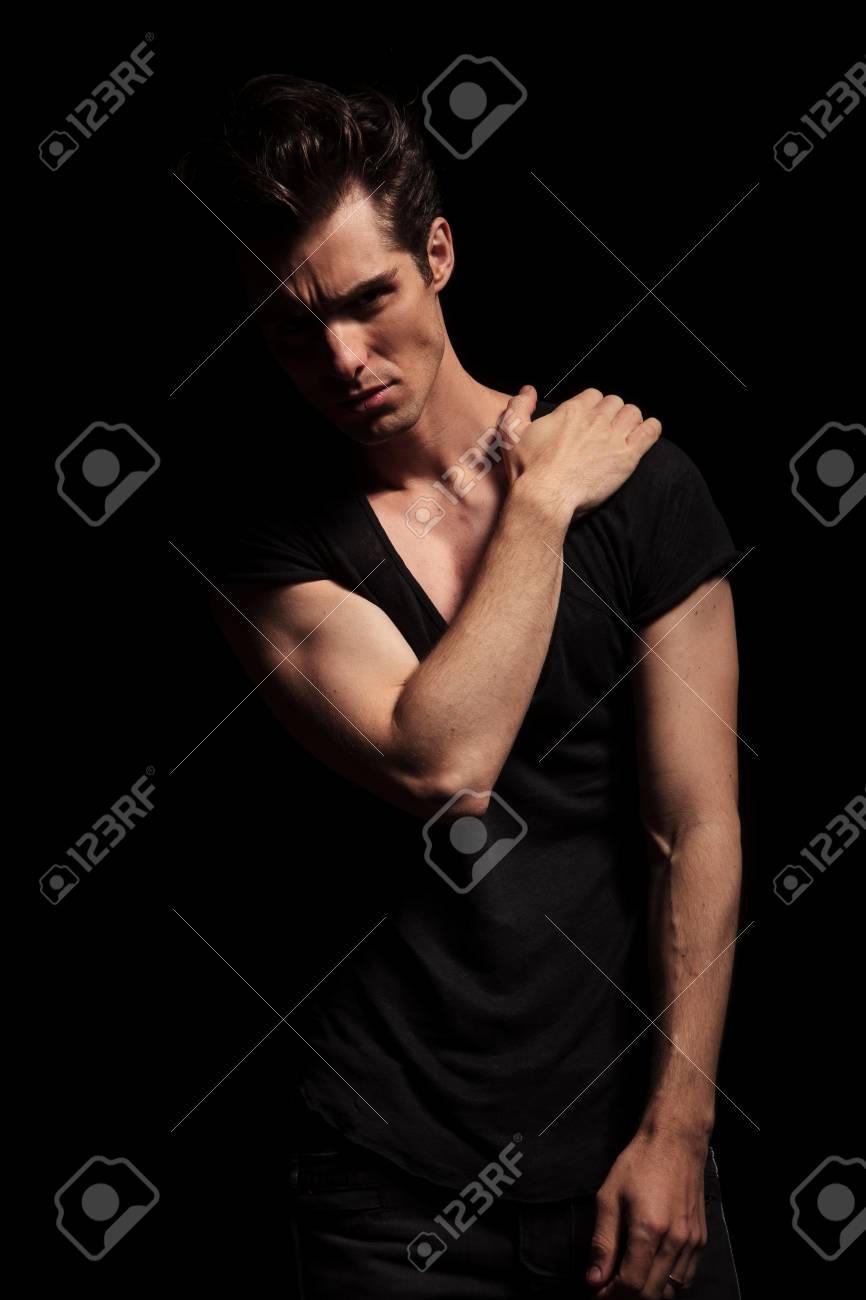 黒の T シャツとジーンズのスタジオでポーズをしながら肩に手を握ってでセクシーな男 の写真素材 画像素材 Image