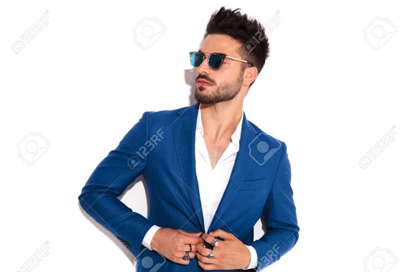 elegant man wearing sunglasses buttoning his suit and looks away to side on white background - 80997671 elegant man wearing sunglasses buttoning his suit and looks away to side on white background - 80997671
