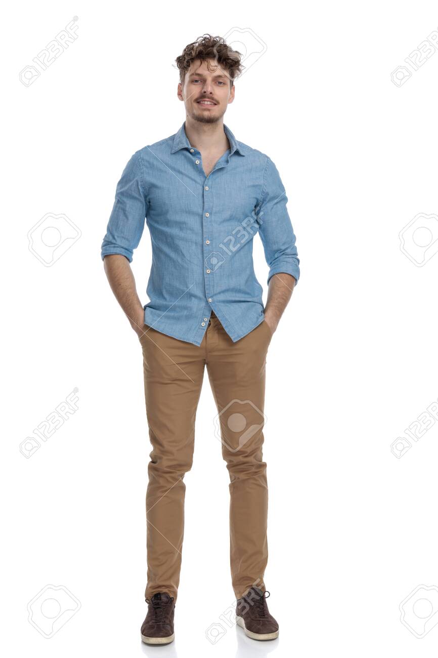 attractive casual guy in denim shirt holding hands in pockets and smiling isolated on white background, full body - 148985103 attractive casual guy in denim shirt holding hands in pockets and smiling isolated on white background, full body - 148985103