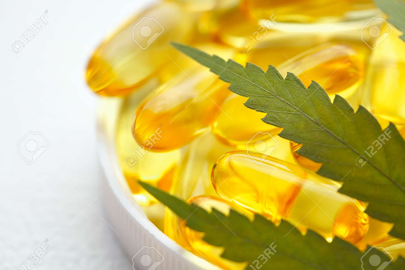 CBD oil capsules and hemp leaves. Macro close up of capsules of biological and ecological hemp plant herbal pharmaceutical cbd oil - 169732223 CBD oil capsules and hemp leaves. Macro close up of capsules of biological and ecological hemp plant herbal pharmaceutical cbd oil - 169732223