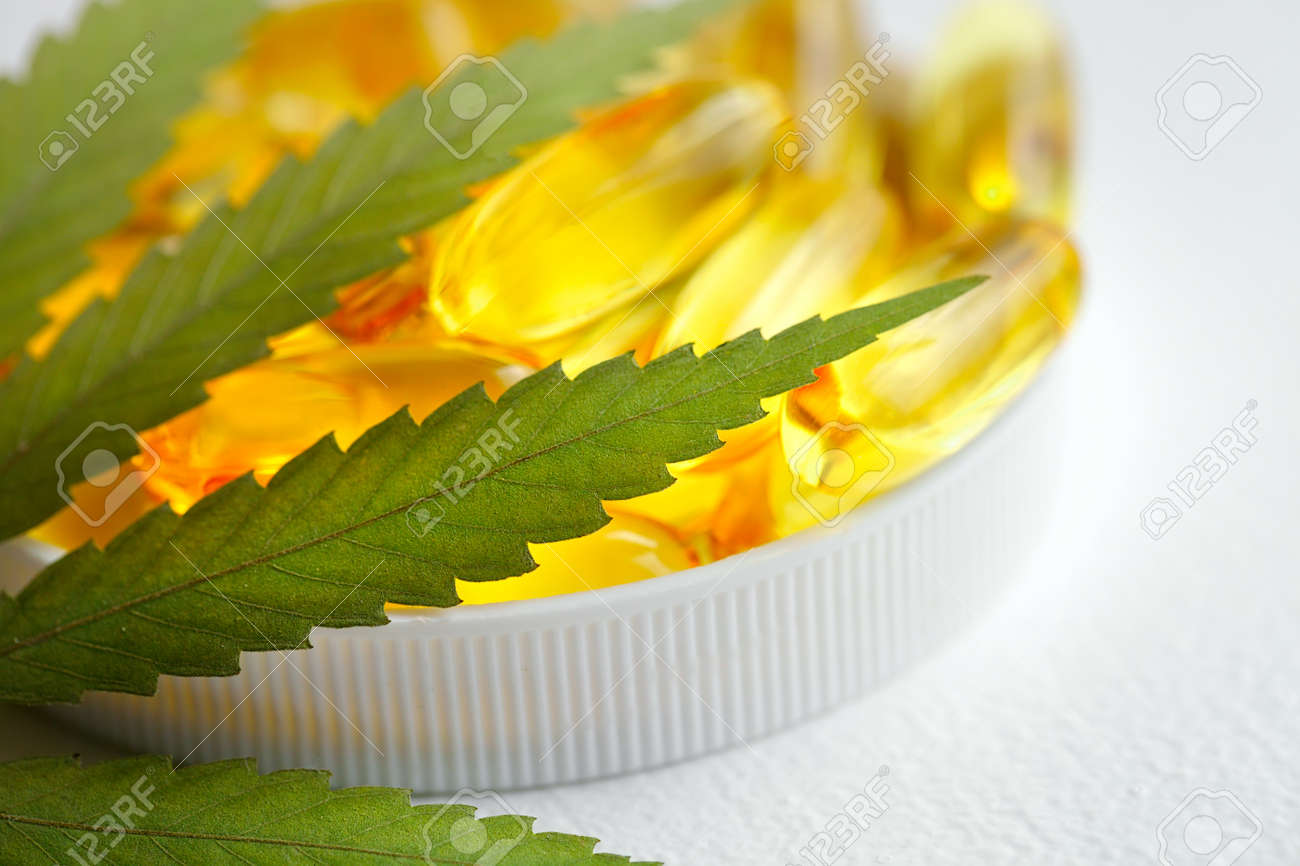 CBD oil capsules and hemp leaves. Macro close up of capsules of biological and ecological hemp plant herbal pharmaceutical cbd oil - 169732097 CBD oil capsules and hemp leaves. Macro close up of capsules of biological and ecological hemp plant herbal pharmaceutical cbd oil - 169732097