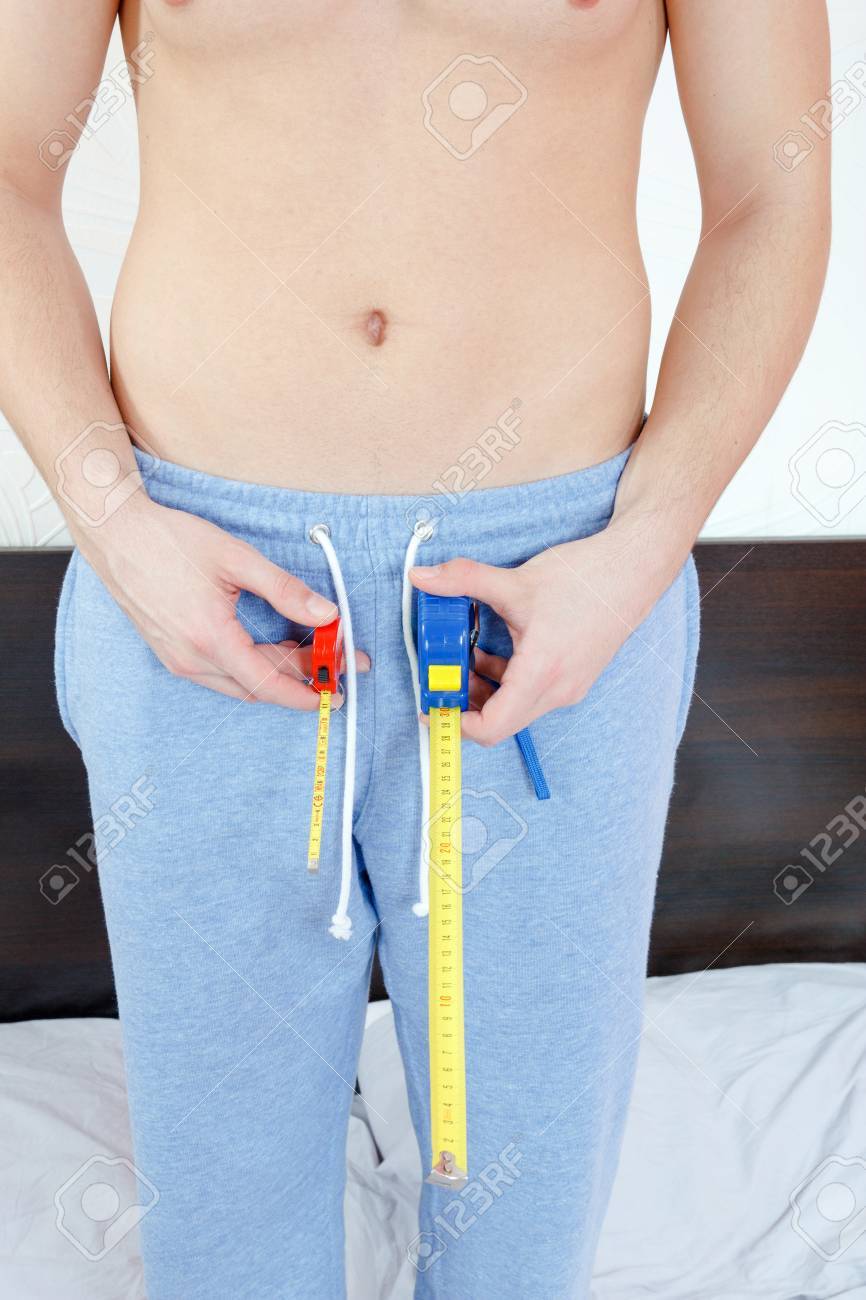 半裸の男がぶら下がっている 2 メートルの手で保持または測定には 長さが望まれます 男性の性器 比較写真の小さく 大きいサイズのコンセプトです の写真素材 画像素材 Image