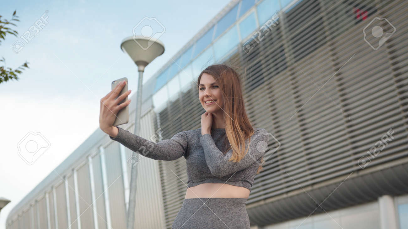 魅力的で幸せな女の子のハメ撮り。スマートフォンを持っている美しいスポーツの女の子のクローズアップ。モダンな建物の背景にビデオチャットをしている若い白人女性のクローズアップ。屋外。  1の写真素材・画像素材 Image 170002511