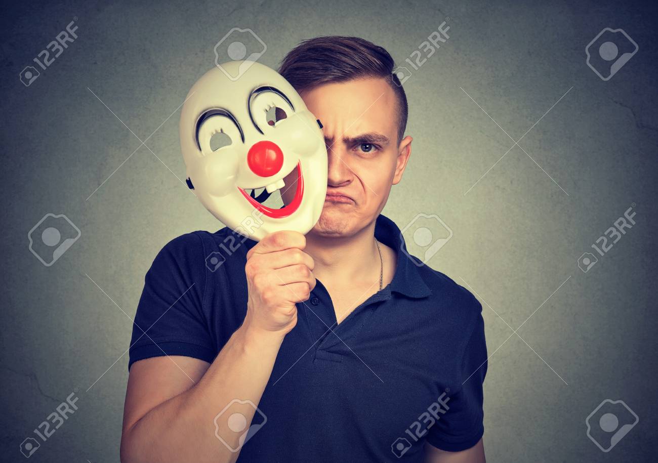 a little mad young negative man hiding real face with clown mask