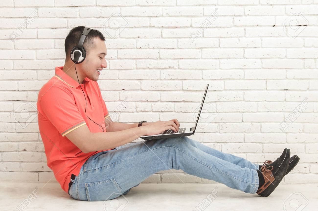 ハンサムな大学生のゲームのラップトップで床に座っての肖像画 の写真素材 画像素材 Image