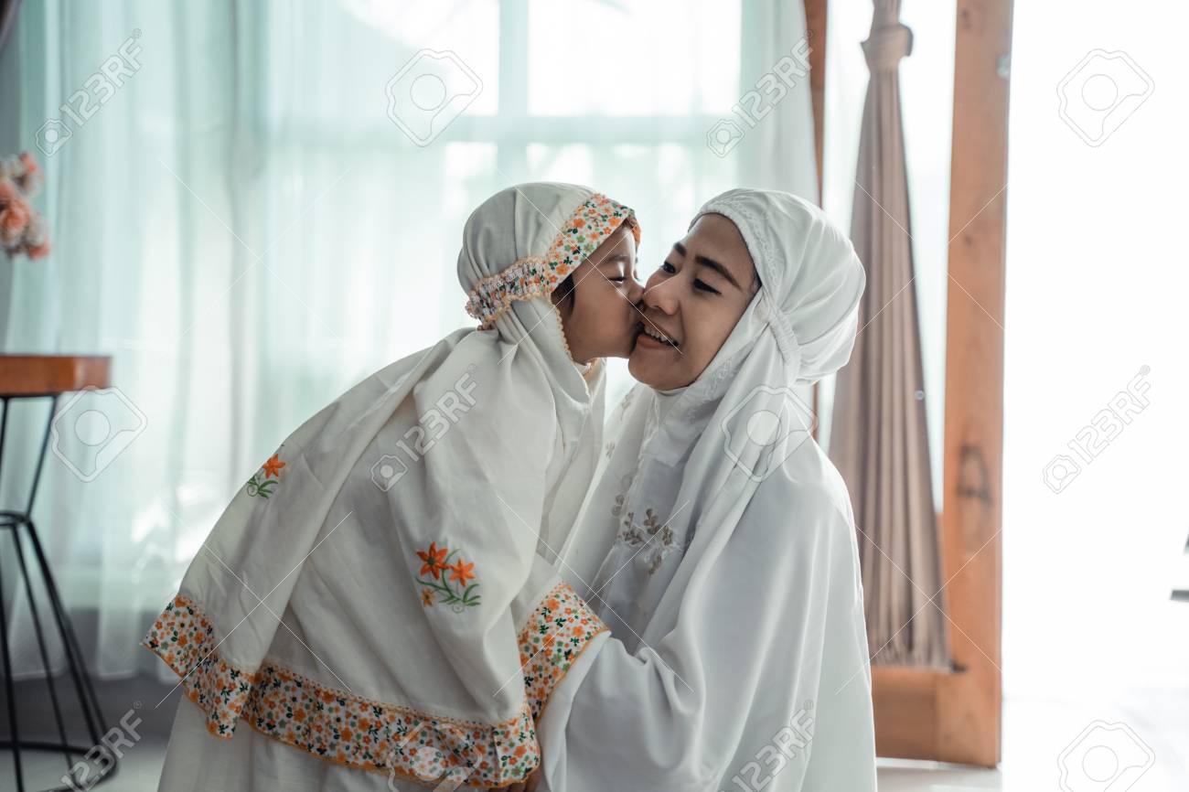 muslim young child kiss her mom after praying - 122175077 muslim young child kiss her mom after praying - 122175077