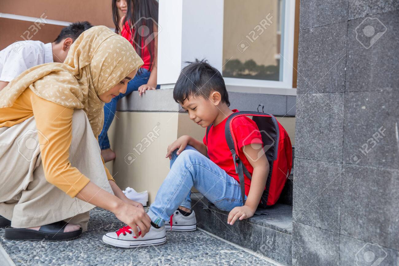 help her son to put on his shoes - 123430468 help her son to put on his shoes - 123430468