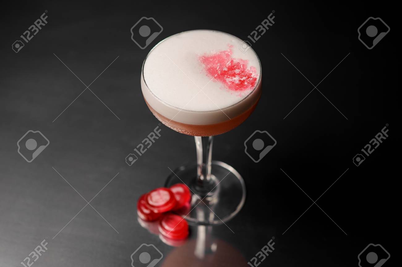 白い泡と甘い酒とカクテル グラス ピンクのキャンディーが暗い面を提供して飾られています 飲み物概念 の写真素材 画像素材 Image