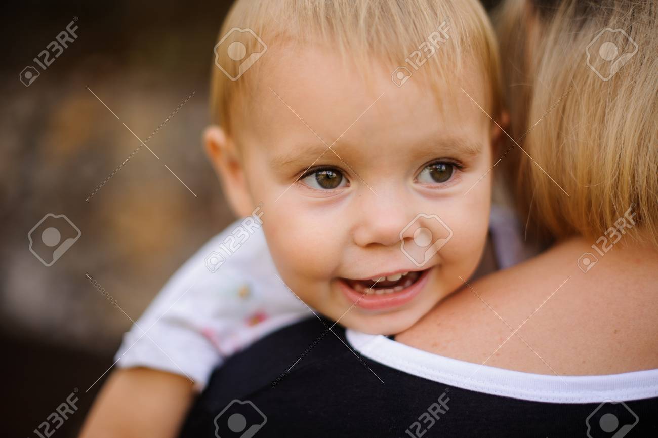 Souriant Et Mignon Bebe Blond Et Aux Yeux Bruns Couche Sur L Epaule De Maman Et Heureusement En Detournant Les Yeux Banque D Images Et Photos Libres De Droits Image