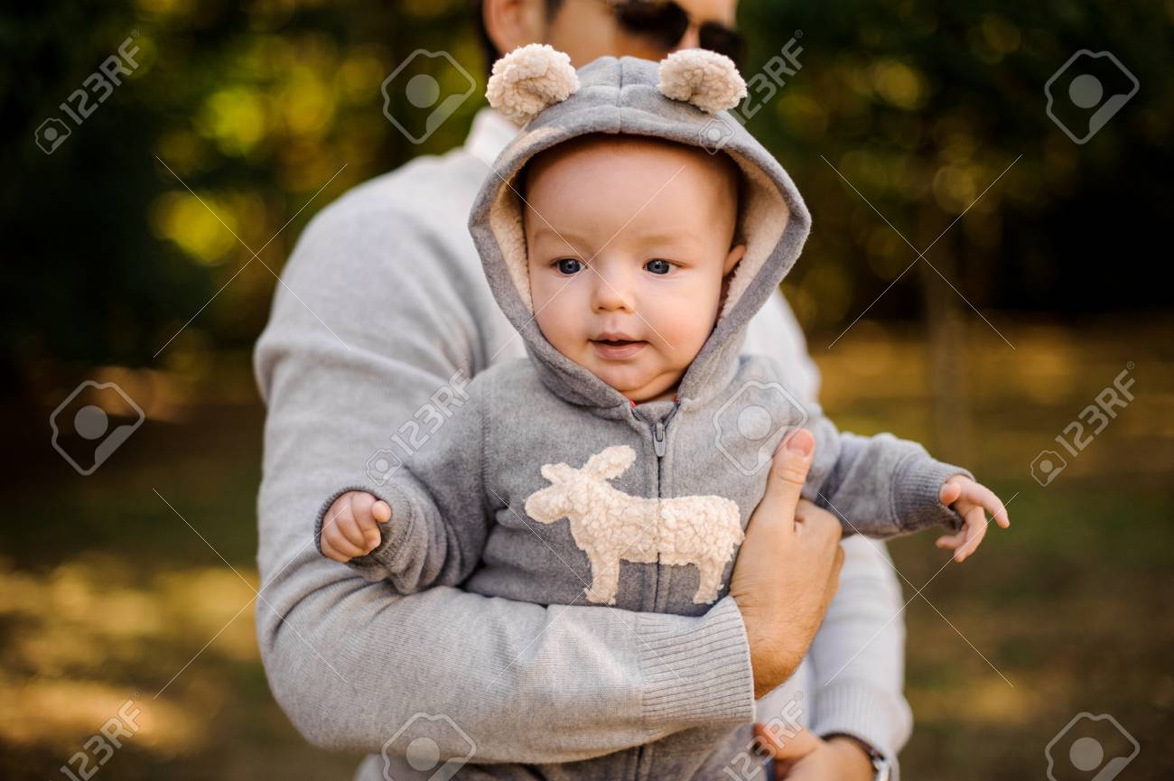 屋外で幸せな若いパパの手に灰色の面白い服を着たかわいい男の子 の写真素材 画像素材 Image