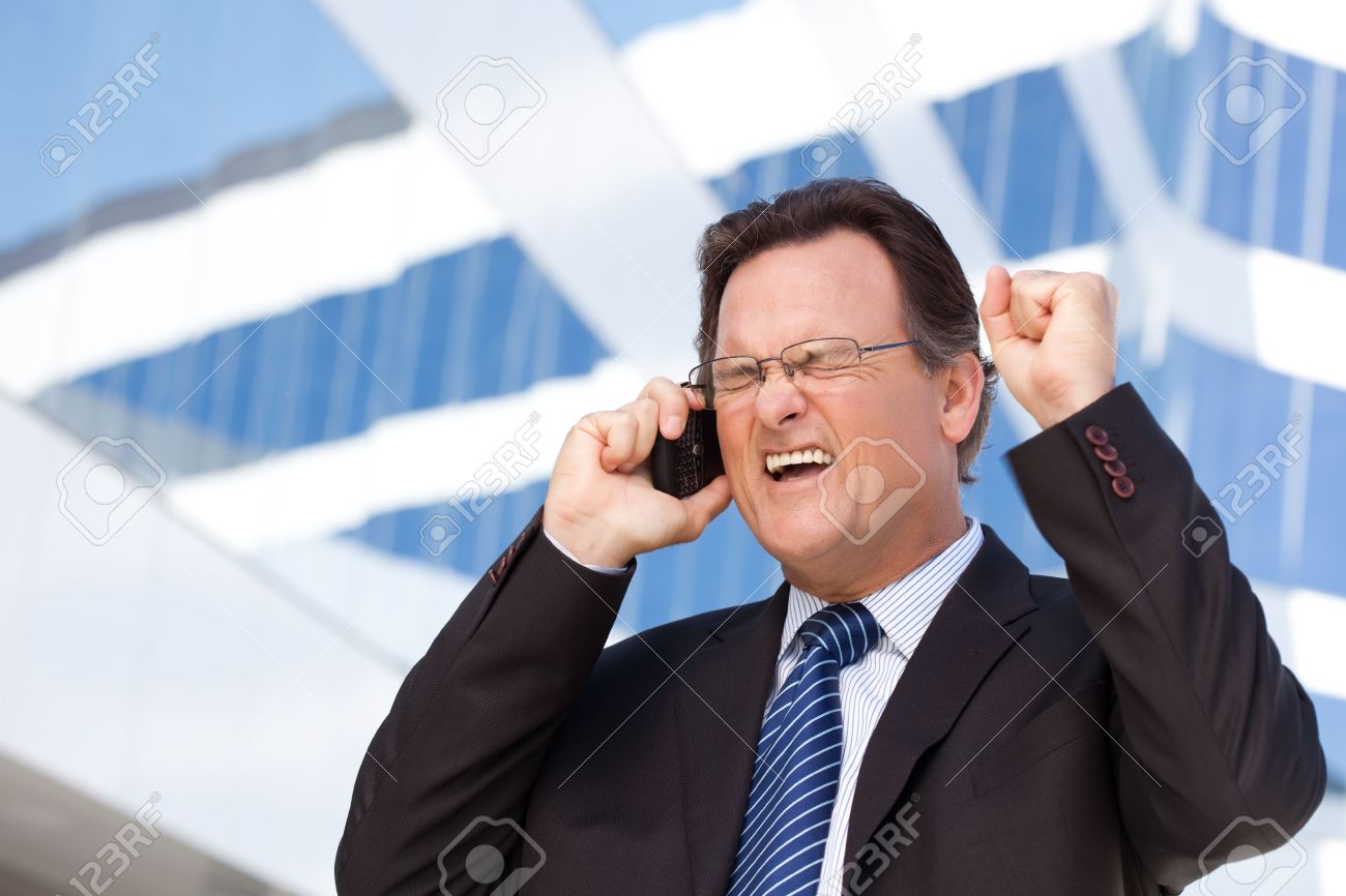 Excited Businessman Using Cell Phone Clinches His Fist in Joy Outside of Corporate Building. - 6633587 Excited Businessman Using Cell Phone Clinches His Fist in Joy Outside of Corporate Building. - 6633587