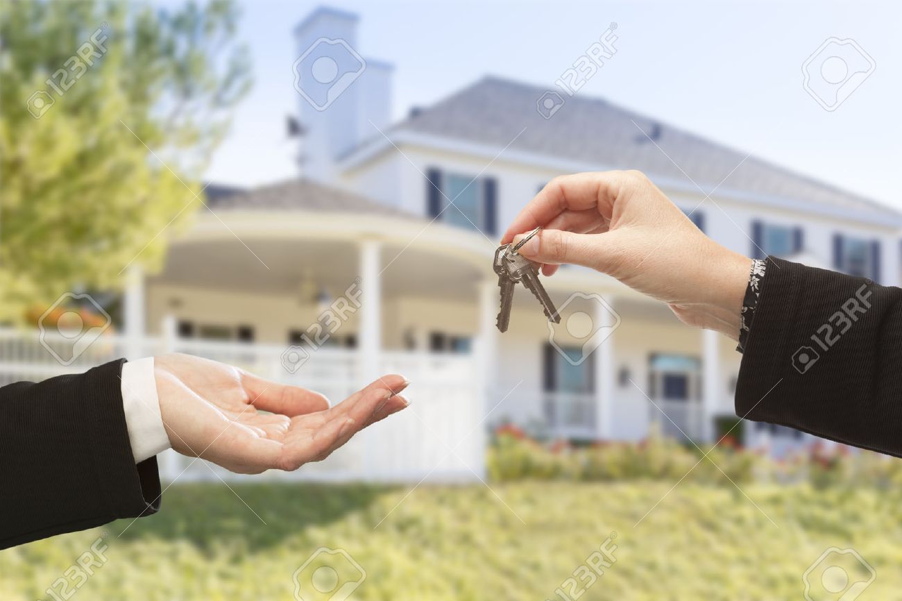 Handing Over The New House Keys With Home In Background Stock Photo Handing Over The New House Keys With Home In Background Stock Photo