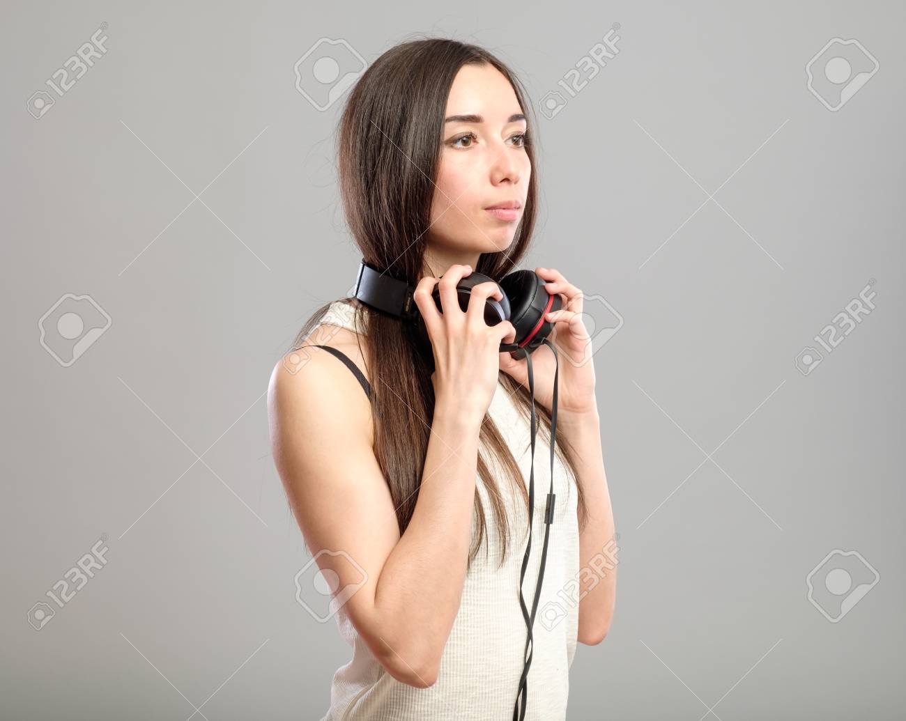 Menina ouvindo música em fones de ouvido na parede rosa. garota