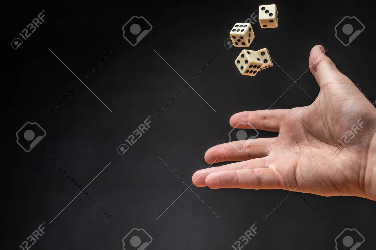 어두운 배경 앞에 주사위를 던지는 손 로열티 무료 사진, 그림, 이미지 그리고 스톡포토그래피. Image 132471091