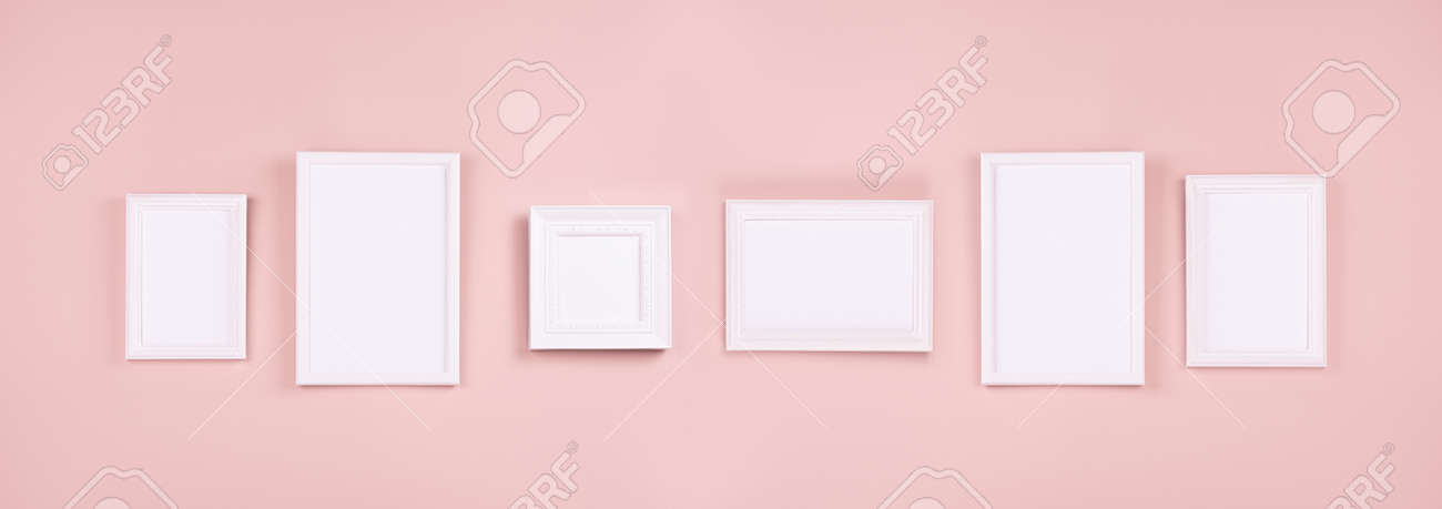 Abstract interior of gallery with set of many different white blank photo frames for text, design, poster, pictures hanging on pastel pink wall, web banner. Mock up for display portfolio. - 168468905 Abstract interior of gallery with set of many different white blank photo frames for text, design, poster, pictures hanging on pastel pink wall, web banner. Mock up for display portfolio. - 168468905