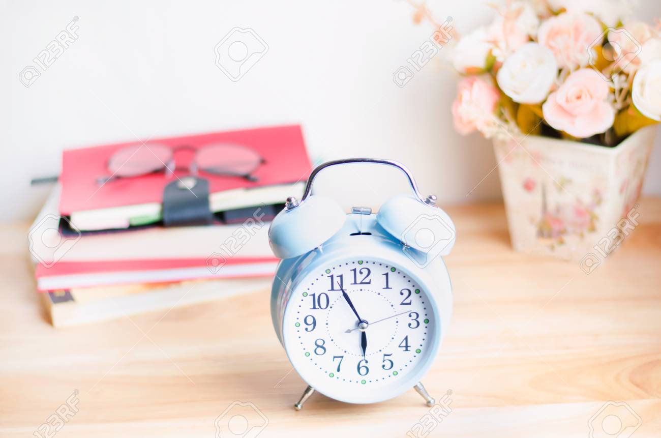Light Blue Alarm Clock On Wooden Table With Books Glasses And Flower In Background Soft Vintage Color Stock Photo Picture And Royalty Free Image Image
