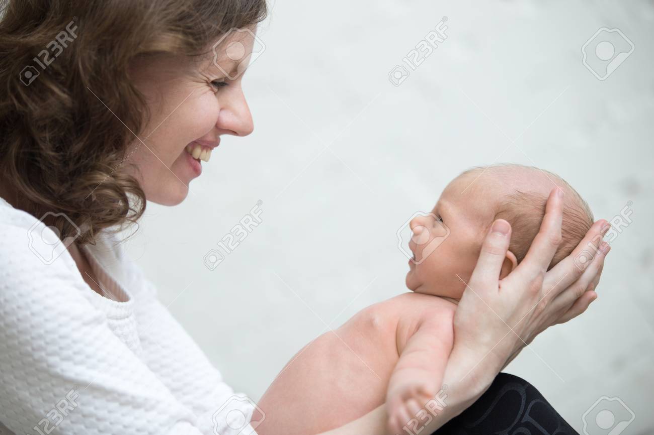 若い母親は保持新生児かわいいかわいい赤ちゃん最初の笑顔について満足しています うれしそうなお母さんと生まれたての子が一緒に遊んで お母さんと小さな子供の健康的な側面の肖像画を表示します 愛 接合 幸せな家族の概念 の写真素材 画像素材 Image