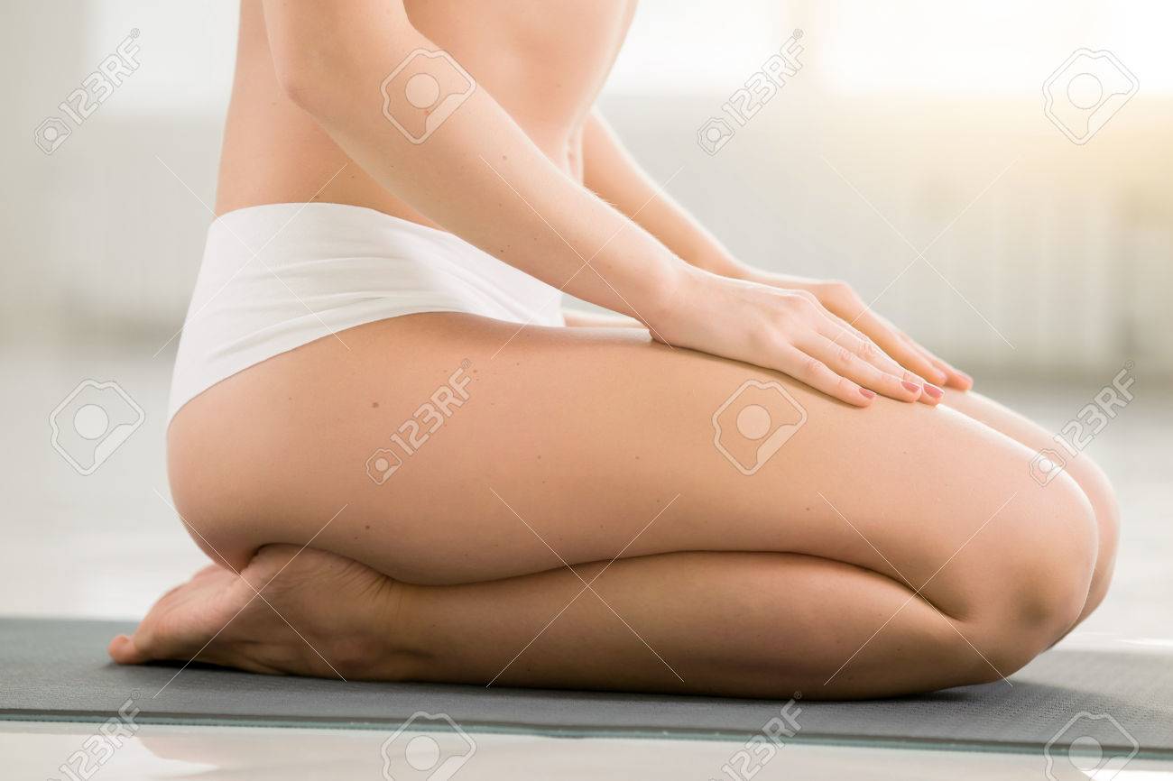 ヨガの練習の若い女性 高い基幹運動 正座で座っているポーズ ワークアウト 身に着けているスポーツウェア ショーツ 屋内 部屋の背景の色を白 足のクローズ アップ の写真素材 画像素材 Image