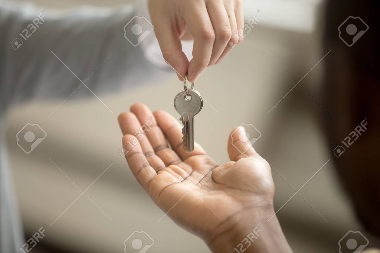 realtor woman giving african american customer hand taking key buying a house for sale by owner with a realtor
