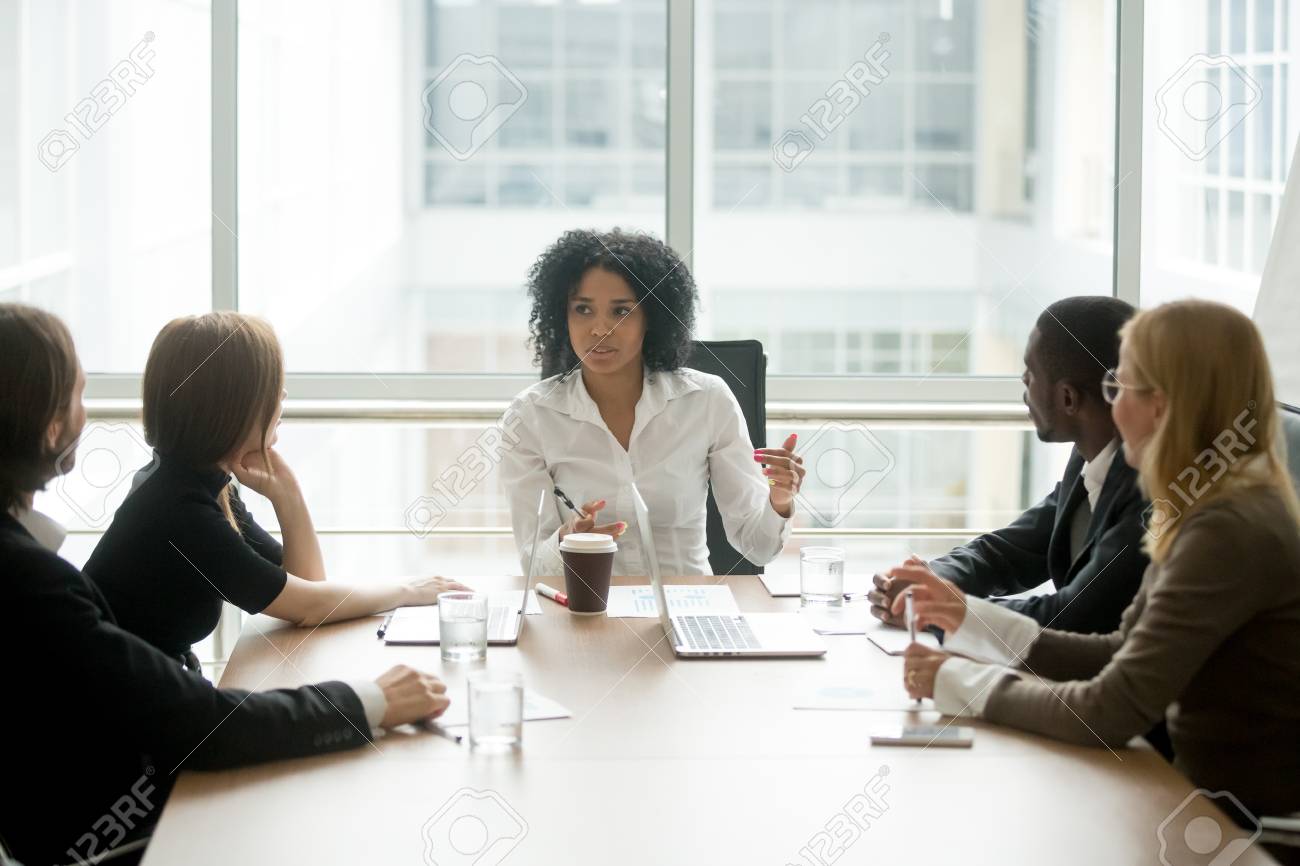 Black female boss leading corporate multiracial team meeting talking to diverse businesspeople, african american woman executive discussing project plan at group multi-ethnic briefing in boardroom - 97035374 Black female boss leading corporate multiracial team meeting talking to diverse businesspeople, african american woman executive discussing project plan at group multi-ethnic briefing in boardroom - 97035374
