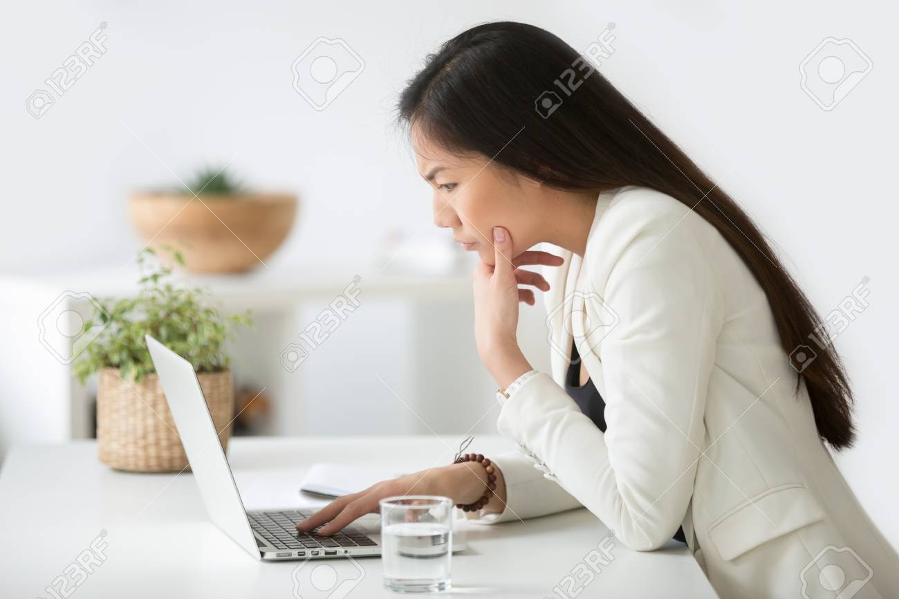 Puzzled confused asian woman thinking hard concerned about online problem solution looking at laptop screen - 101473293 Puzzled confused asian woman thinking hard concerned about online problem solution looking at laptop screen - 101473293