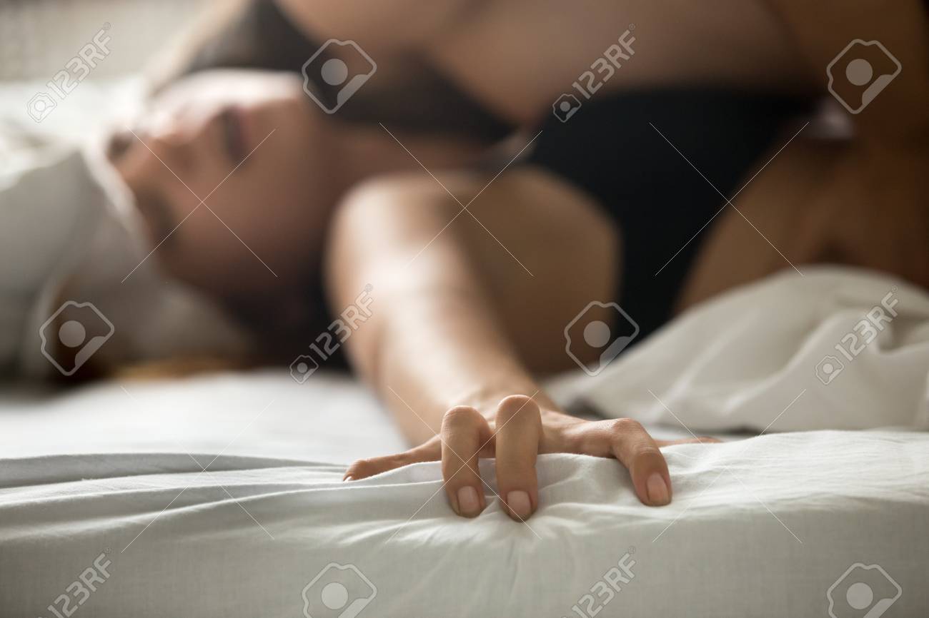 Close Up Of Satisfied Woman Hand Holding Bed Feeling Having With Lover, Passionate Couple Making Love On White Sheets In Bedroom, Woman Moaning With Pleasure Or Ecstasy, Enjoying Stock Photo, Picture