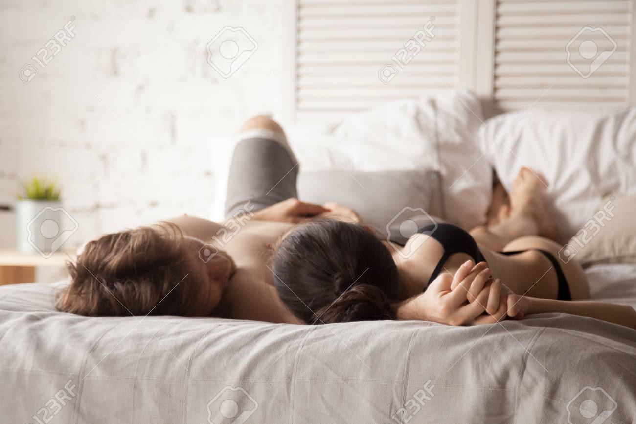 Casal Amoroso Sensual Deitado Na Cama Juntos, De Mãos Dadas Após O Sexo,  Namorada E Namorado Se Abraçam Depois De Apaixonados Fazendo Amor,  Desfrutando De Um Momento Romântico Em Casa, Homem E