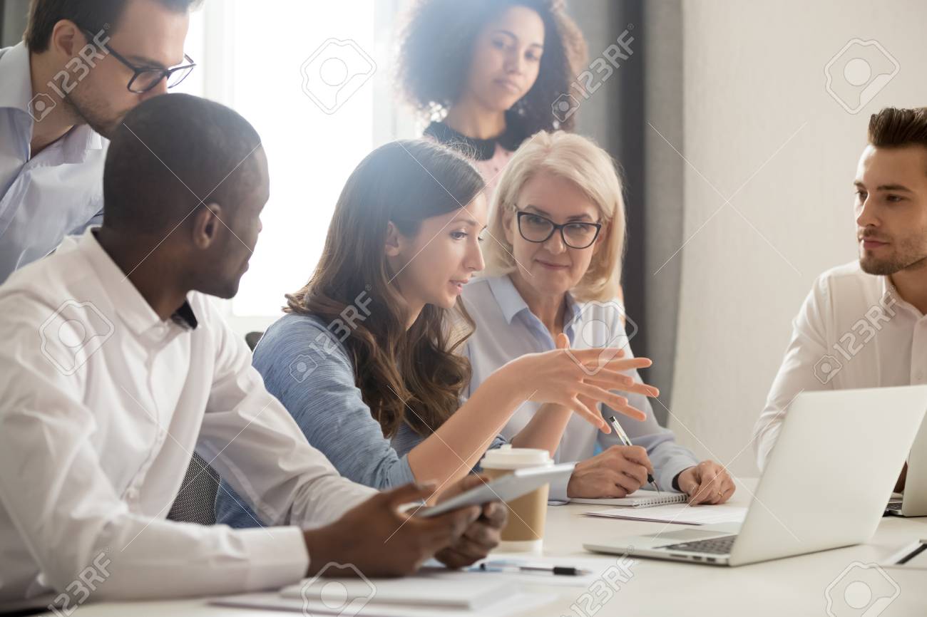 Young female mentor leader coach teaching employees group analyzing online project explaining business strategy speaking training diverse corporate team with laptop using computer at office meeting. - 119154625 Young female mentor leader coach teaching employees group analyzing online project explaining business strategy speaking training diverse corporate team with laptop using computer at office meeting. - 119154625