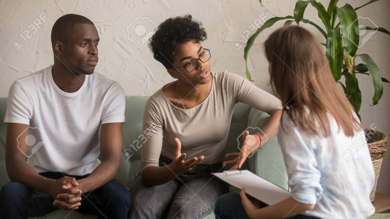 Unhappy jealous mixed-race wife talk to psychologist counselor complain on bad relationship with husband, african american family couple counseling have conversation about problem at therapy session - 120572316 Unhappy jealous mixed-race wife talk to psychologist counselor complain on bad relationship with husband, african american family couple counseling have conversation about problem at therapy session - 120572316