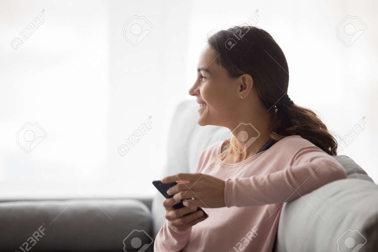 Profil Kobiety Uśmiechnięta Twarz Odwraca Wzrok Odpoczywając Na Sofie Dzień  Planowania Wypełniony Pozytywnymi Wspomnieniami Dziewczyna Trzyma Telefon  Otrzymał Dobre Wieści Zadowolony Użytkownik Urządzenia Nowa Bezpłatna  Aplikacja E Randki Koncepcja ...