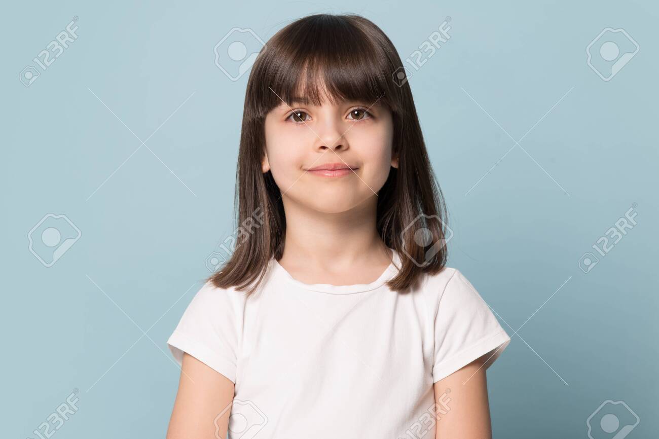Adorable six years old girl in white t-shirt isolated on blue studio background, pretty brown-haired fringe hairstyle european appearance child pose indoor smiling look at camera, generation Z concept - 124555005 Adorable six years old girl in white t-shirt isolated on blue studio background, pretty brown-haired fringe hairstyle european appearance child pose indoor smiling look at camera, generation Z concept - 124555005
