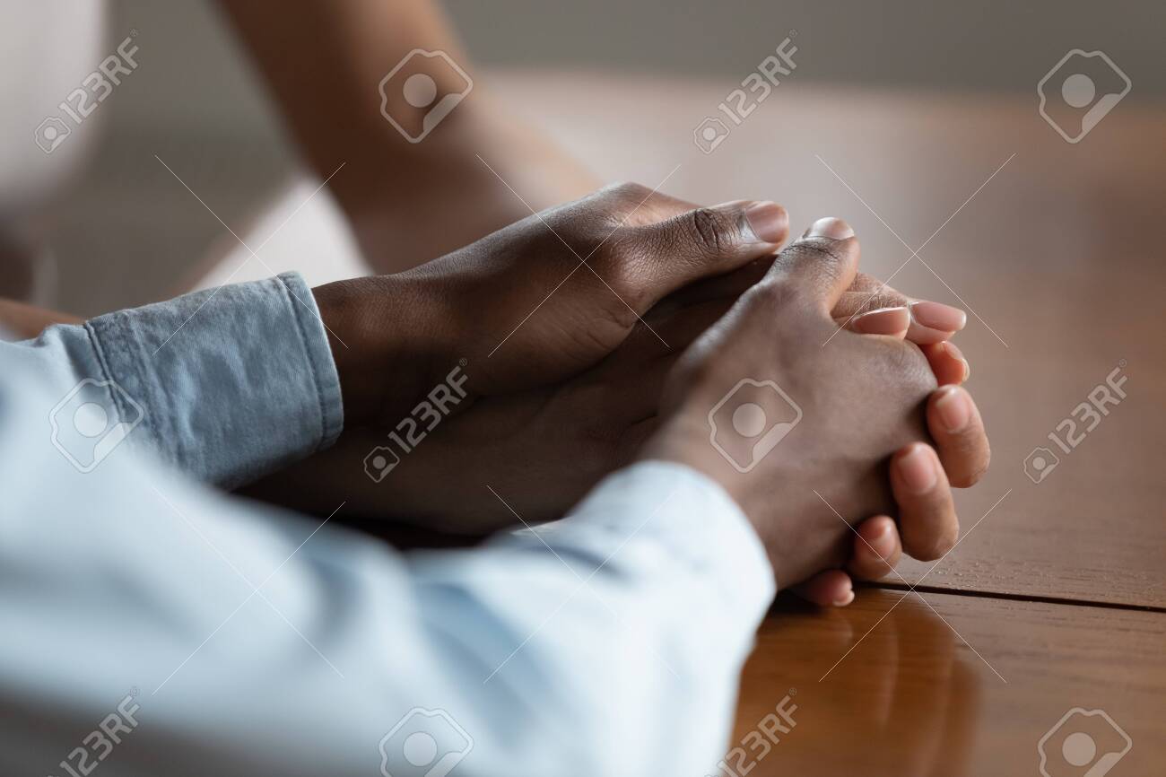 Close up of african American couple hold hands on wooden table make peace reconcile after fight, biracial husband and wife show love, care and support, have romantic intimate moment. Devotion concept - 129610676 Close up of african American couple hold hands on wooden table make peace reconcile after fight, biracial husband and wife show love, care and support, have romantic intimate moment. Devotion concept - 129610676
