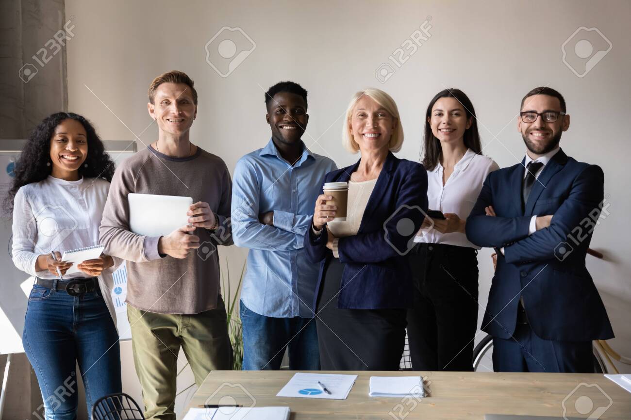 Happy confident diverse old and young business people stand together in office, smiling multiethnic professional colleagues staff group look at camera, human resource concept, team corporate portrait - 132157592 Happy confident diverse old and young business people stand together in office, smiling multiethnic professional colleagues staff group look at camera, human resource concept, team corporate portrait - 132157592