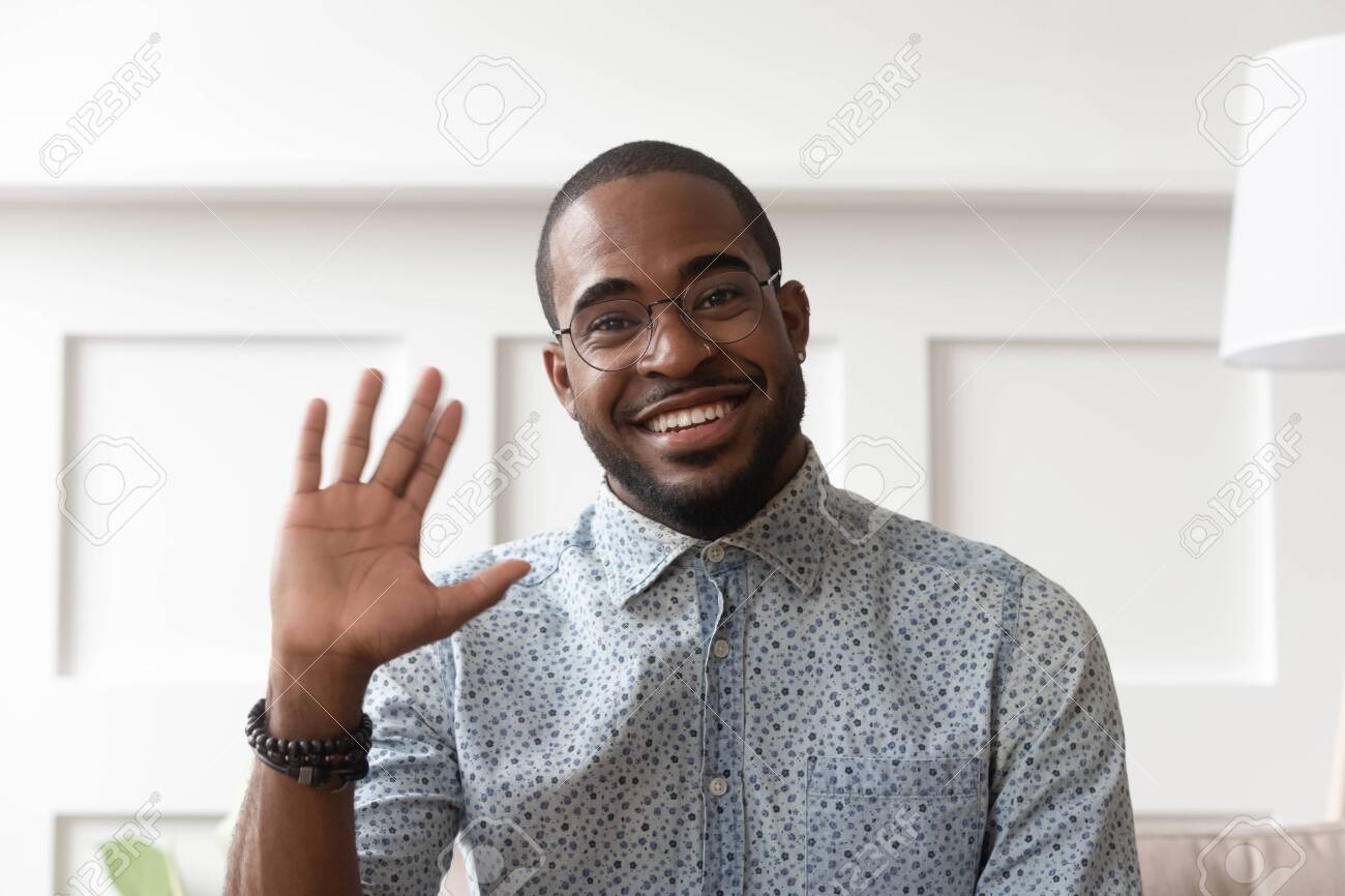 Smiling African American Millennial Man In Glasses Look At Camera Waving Saying Hello Talking On Video Call Happy Black Male Vlogger In Spectacles Greeting With Subscribers Shooting Video Blog Stock Photo Picture