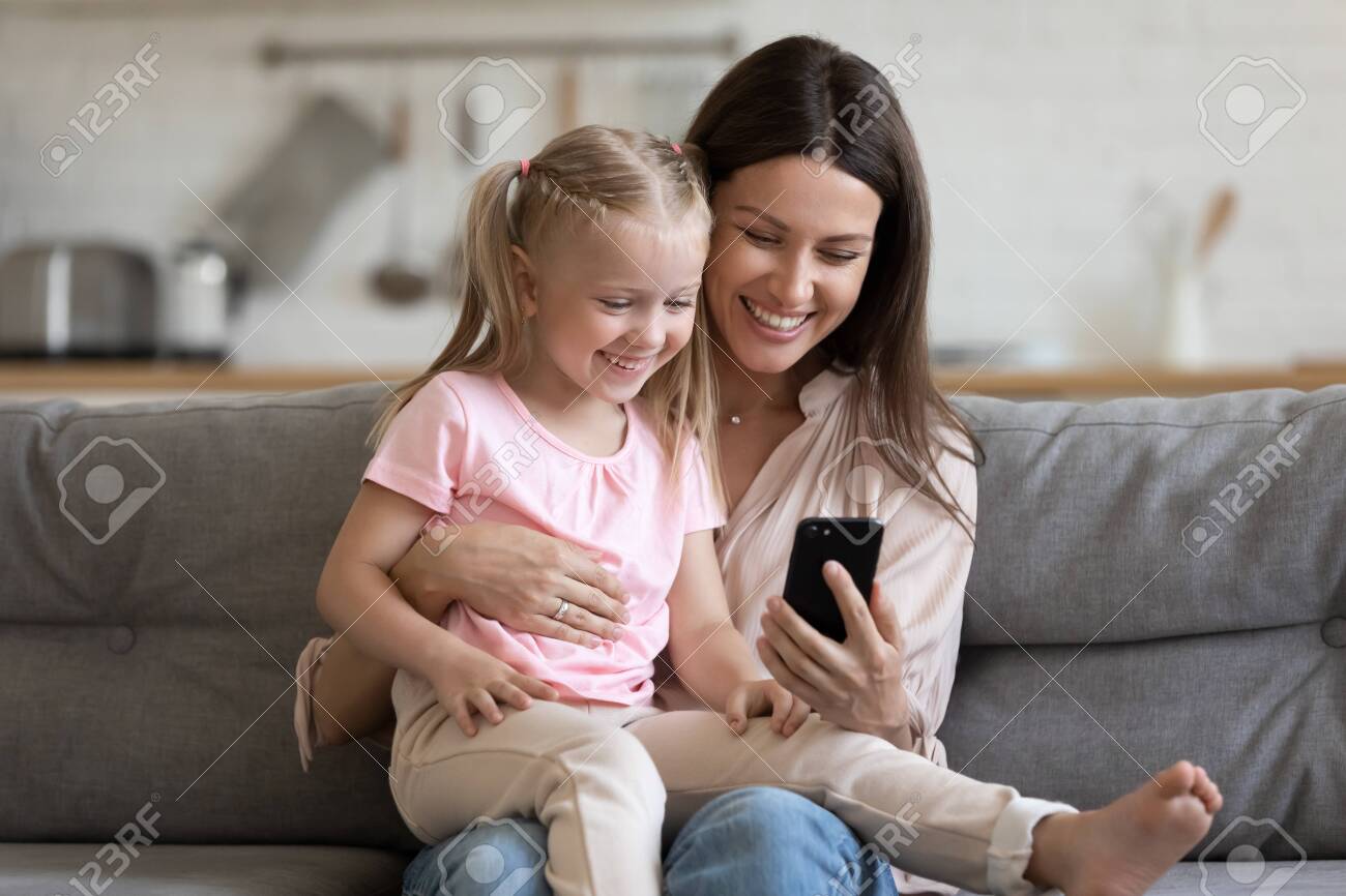 Happy Family Cute Small Kid Child Daughter Sit On Parent Mom Lap On Sofa Laugh Having Happy Family Cute Small Kid Child Daughter Sit On Parent Mom Lap On Sofa Laugh Having