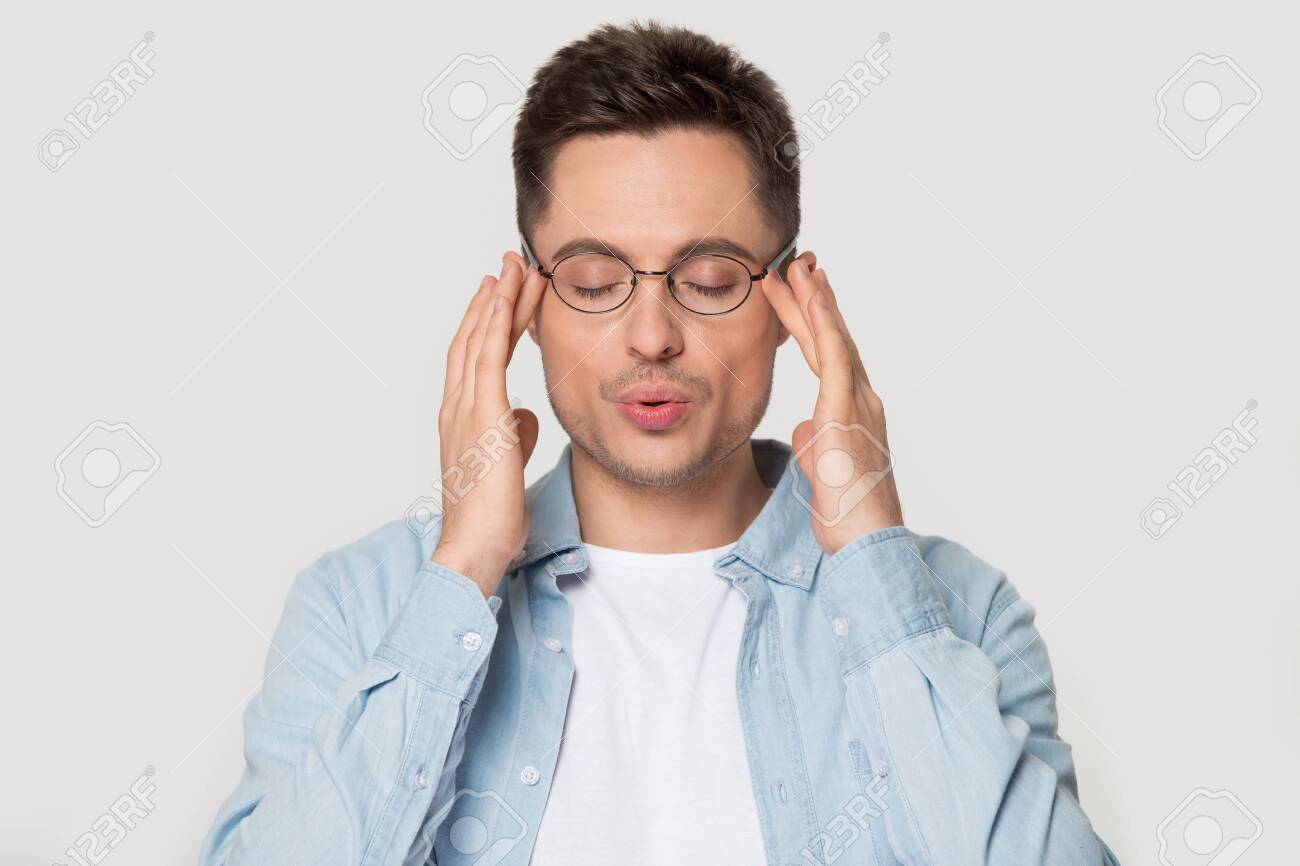 Young Caucasian Man In Eyeglasses Massaging Temples With Close Eyes, Breathing  Out, Trying To Calm Down, Posing On Grey Studio Background Head Shot  Portrait, Reducing Stress, Self-control Concept. Stock Photo, Picture And