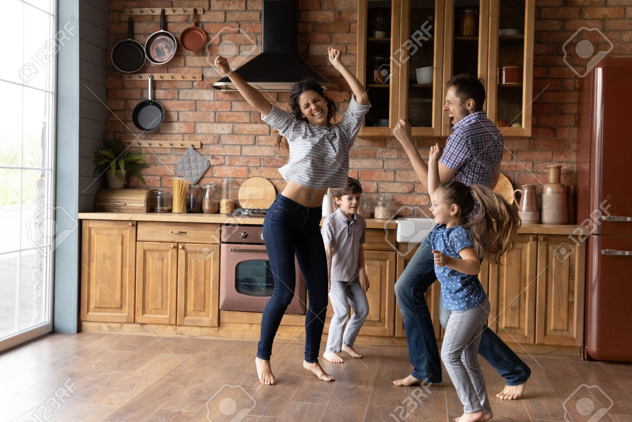 かわいい　中学生裸足 裸足で踊る。音楽のダンスを楽しんでいる幼い娘の息子と一緒に大喜びのミレニアル世代の家族。アクティブなママのお父さんと2人の中学生がキッチンにジャンプして新しい家に引っ越すことを祝うの写真素材・画像素材  Image 160911602
