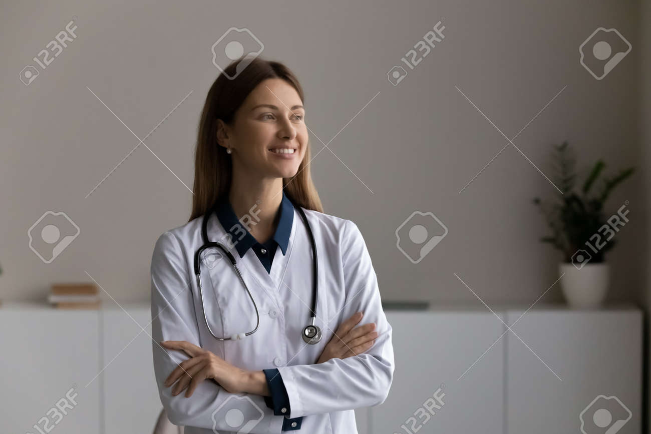 Em guarda da saúde dos pacientes. confiável otimista jovem mulher médica enfermeira terapeuta familiar clínico ficar no escritório da clínica com os braços cruzados olhar para o planejamento à distância pensando sonhar. - 179297604 Em guarda da saúde dos pacientes. confiável otimista jovem mulher médica enfermeira terapeuta familiar clínico ficar no escritório da clínica com os braços cruzados olhar para o planejamento à distância pensando sonhar. - 179297604