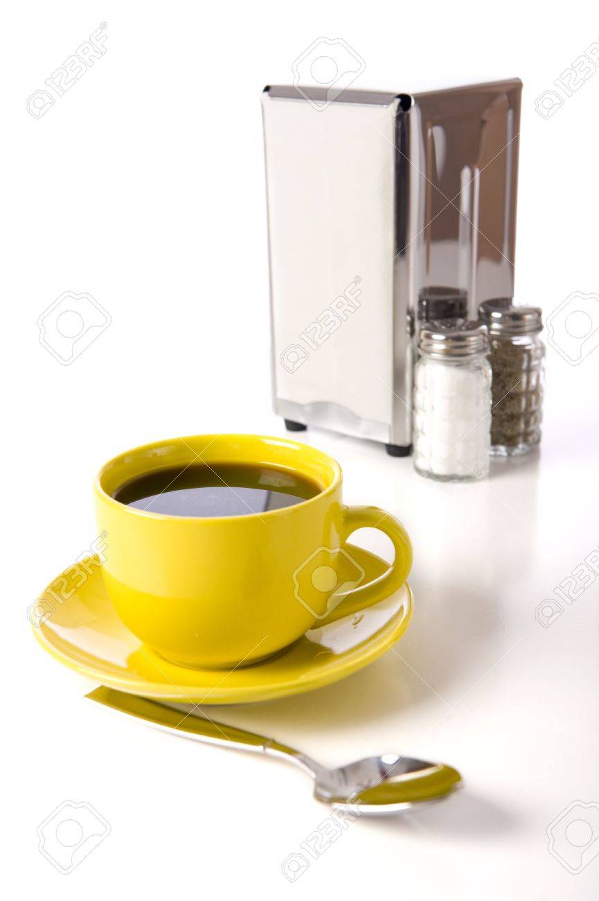 A Cafe Or Coffee Shop Tabletop Setup With A Yellow Cup And Saucer