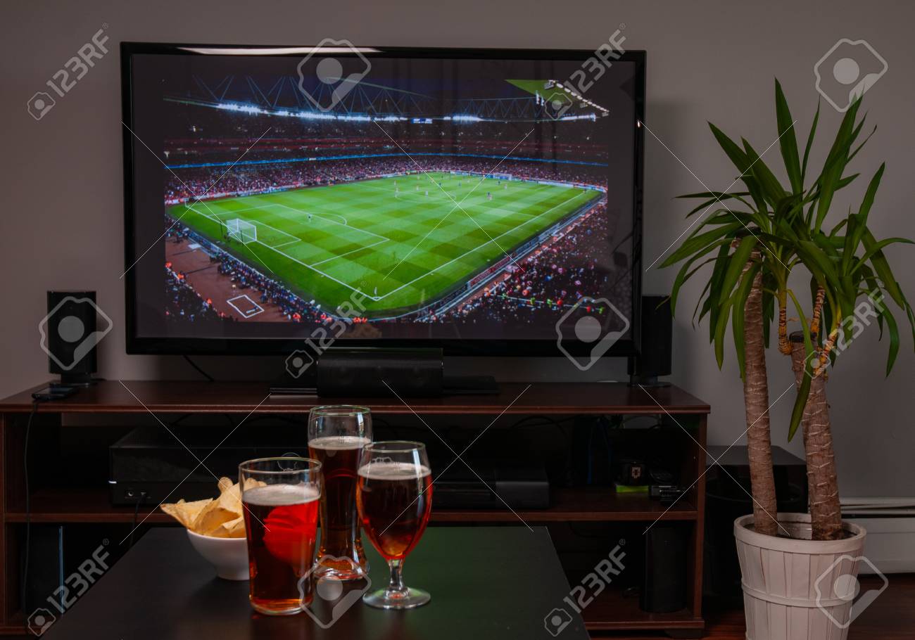 Beer glasses and chips in front of tv, football at home, soccer supporters - 122095478 Beer glasses and chips in front of tv, football at home, soccer supporters - 122095478