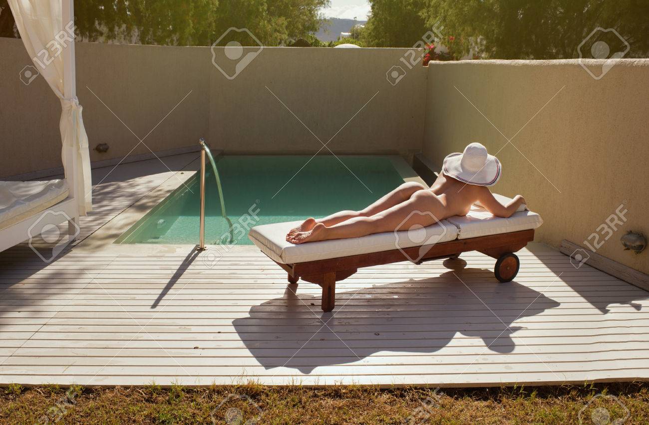 Belle Fille Nue Est Allongée Sur Un Transat Au Bord De La Piscine Et  Bronzer Au Coucher Du Soleil Banque D'Images et Photos Libres De Droits.  Image 74763313
