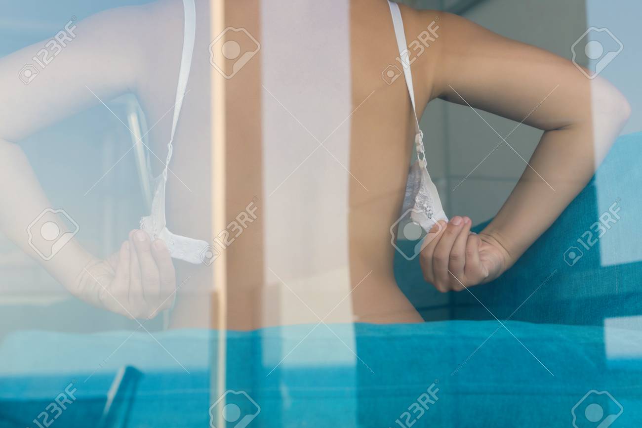 Naked Woman Taking Off Or Putting On Bra Behind The Glass. Stock Photo,  Picture and Royalty Free Image. Image 117774632., woman putting on bra